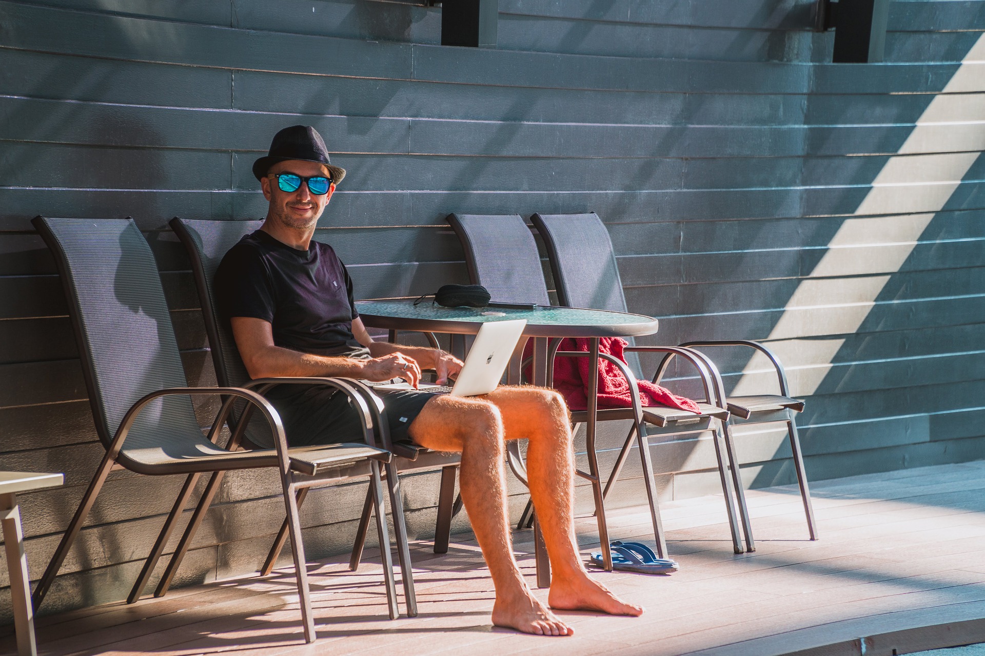 Mann mit Laptop am Pool